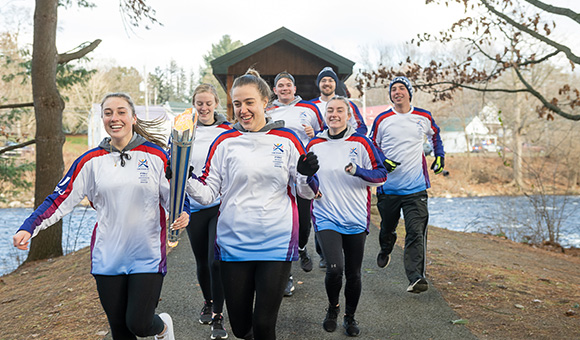 SUNY Canton athletes carry the torch from the footbridges onto campus.