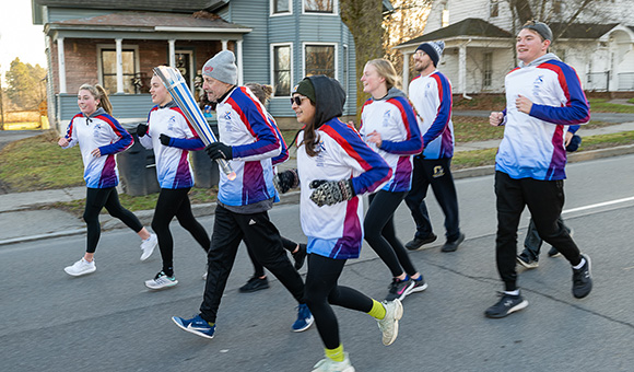 SUNY Canton athletes join Canton marathoner as the run the FISU torch down Main Street.