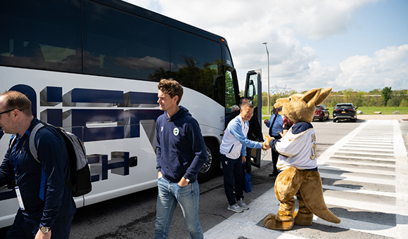 Roody the Roo shakes hands with FISU Senior Event Manager Jiho Kim outside SUNY Canton Roos House Convocation, Athletic & Recreation Center