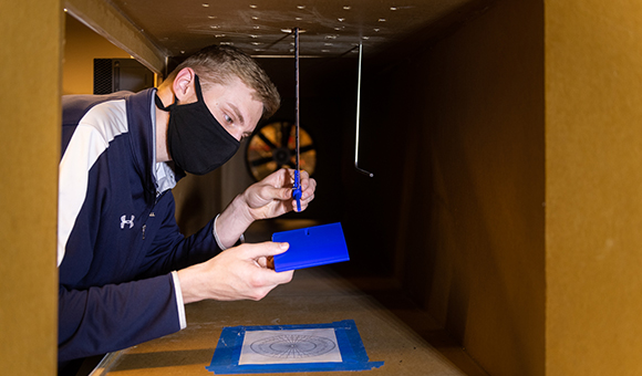 Andrew Fitch attaches an instrument inside the campus wind tunnel.