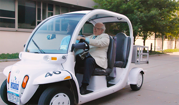 President Szafran drives a GEM car around campus.