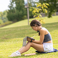 A student sketches on an iPad while sitting on the lawn outside Nevaldine Hall.