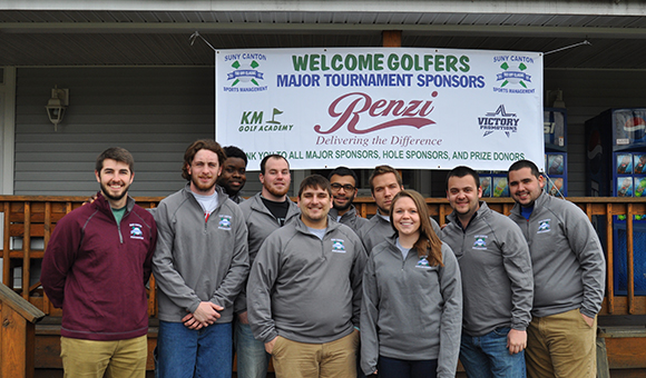 Students pose in front of Tournament banner.