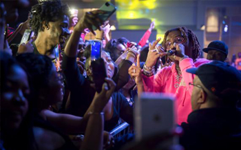 Gunna performs while an audience of students looks on.