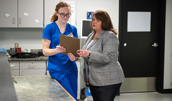 Vicki Perrine works with a student in a hospital office.