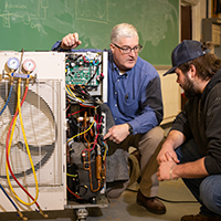 Dean Michael Newtown discusses heat pumps with a student.