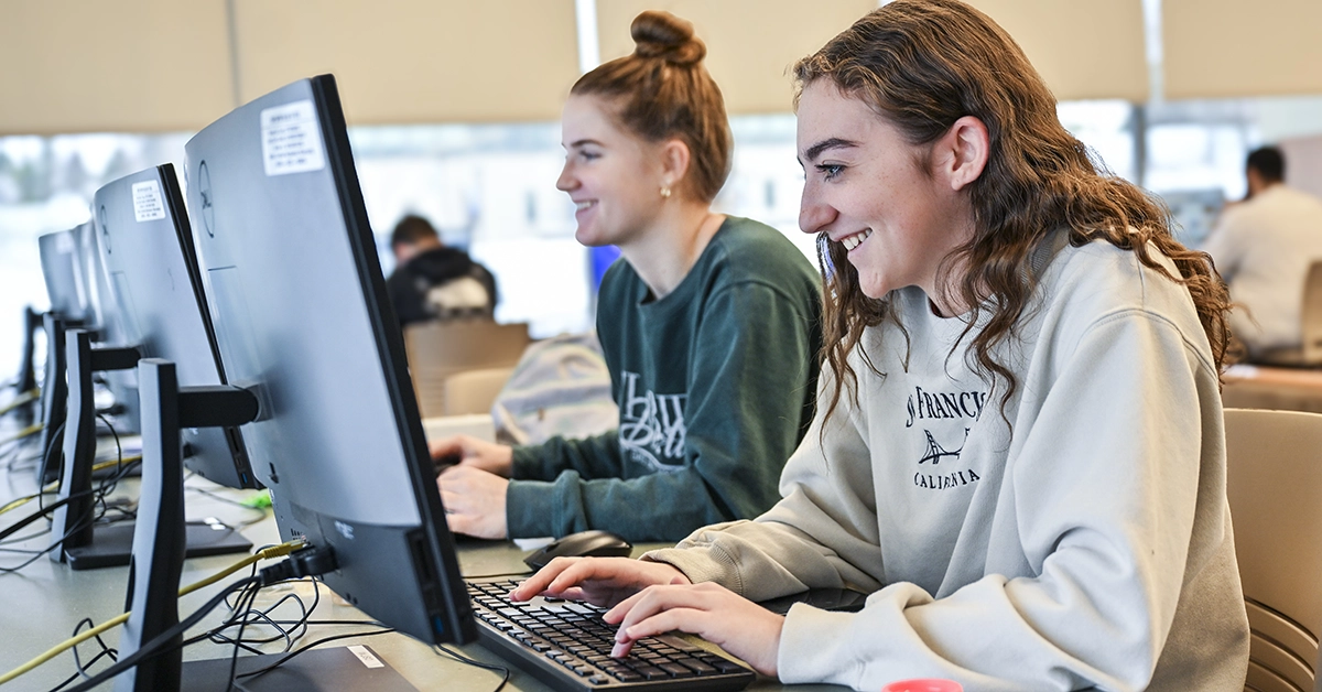 Two students work on desktop computers in the Southworth Library.