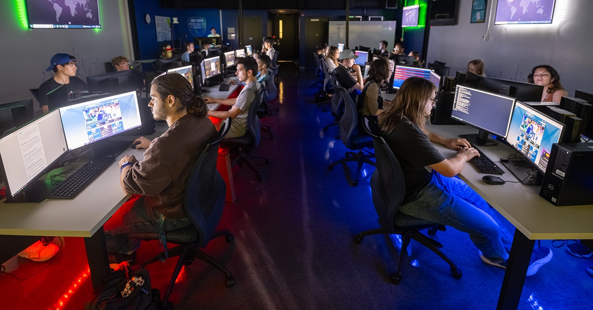 A class works in the Cybersecurity lab while red and blue LEDs light up the underside of each desk.