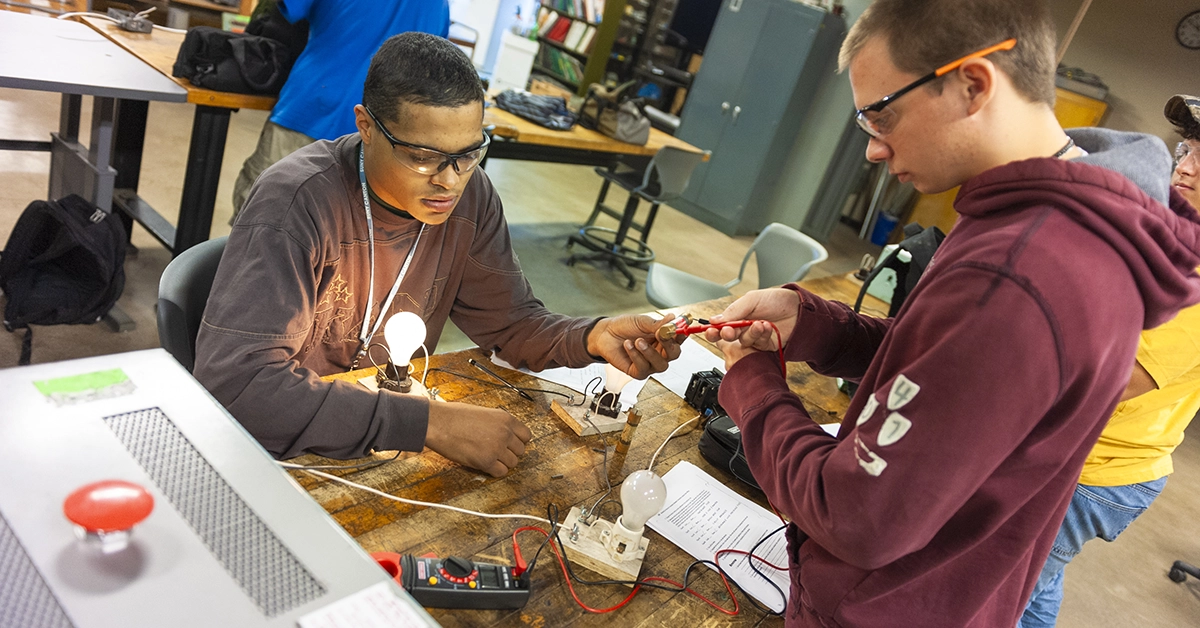 Two students test wiring to lightbulbs in the Electrical Construction lab.