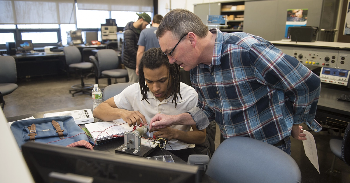 Dave Hartle helps a student wire a small motor in the Electrical Technology lab.