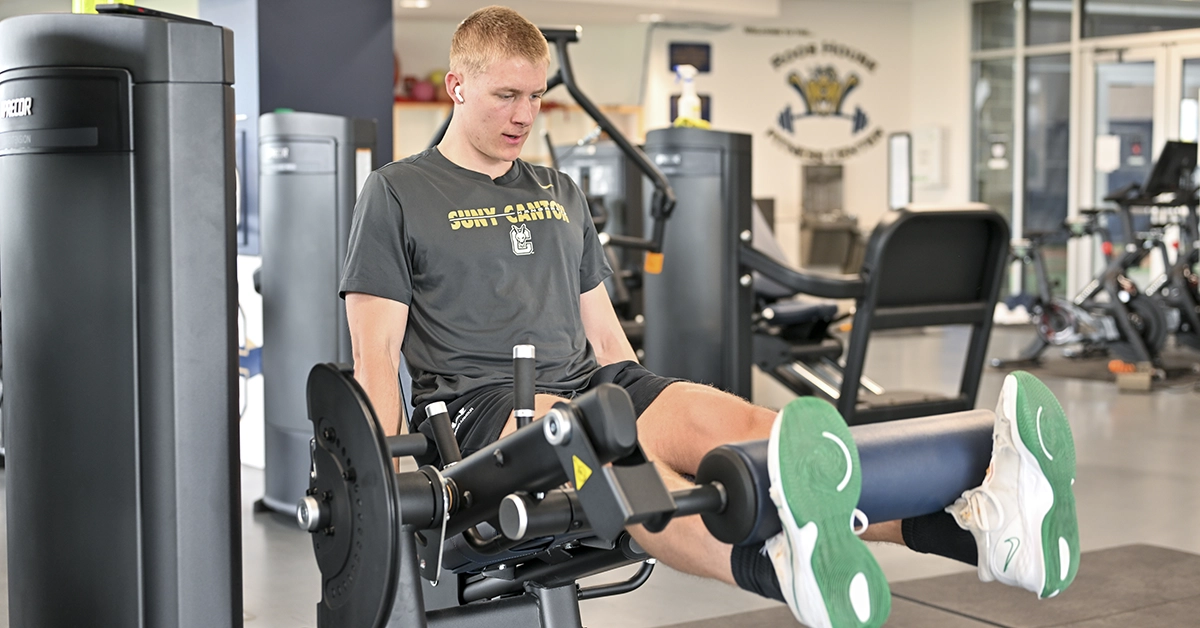 A student extends his legs on a leg press machine.