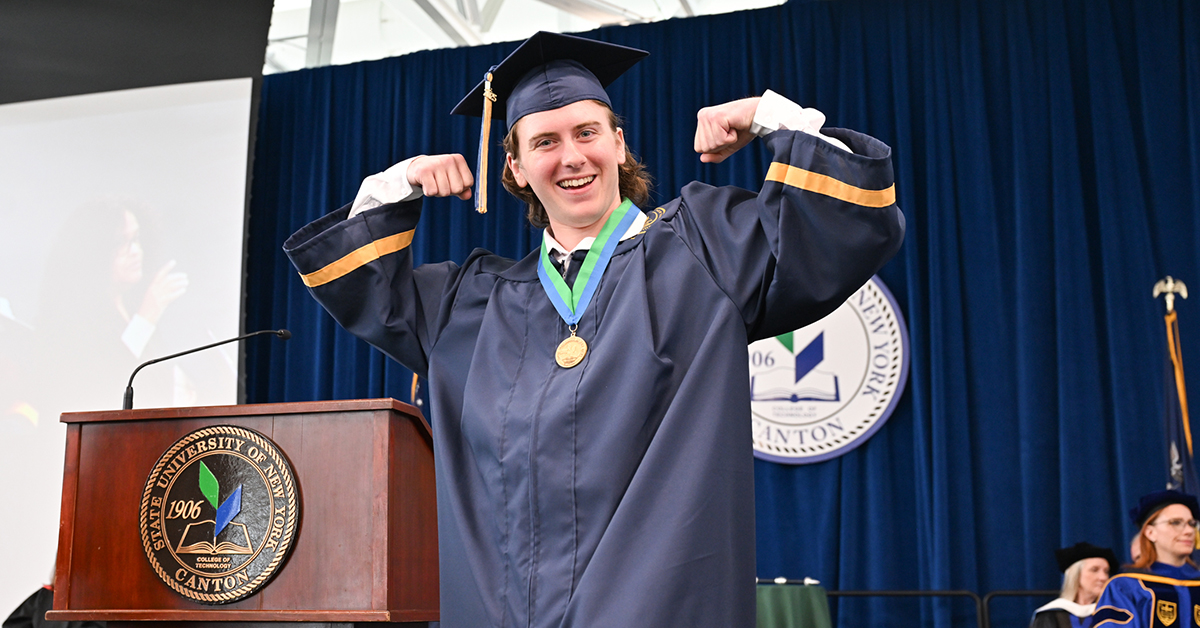 A graduate flexes his muscles while on stage during Commencement 2025.