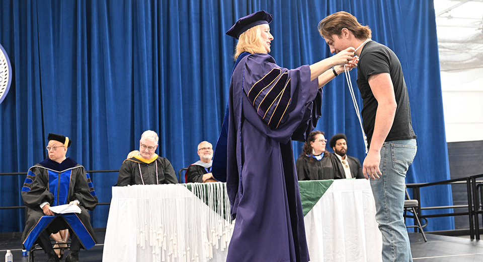Dean Michele Snyder places an honors cord around a student.