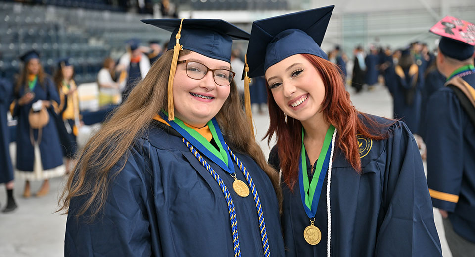 Two students smile in the Ice Arena prior to Commencement 2024.