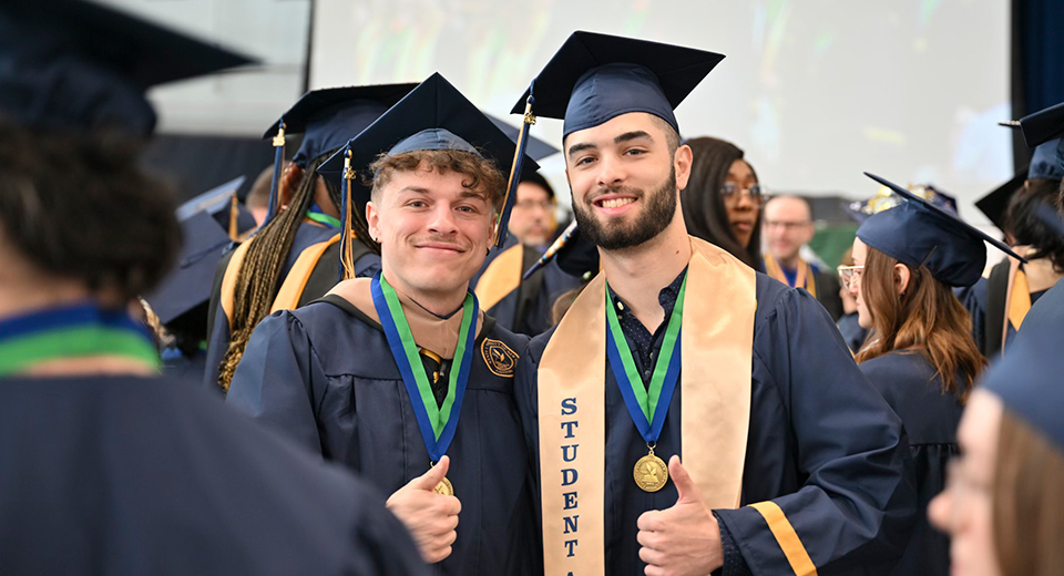 Two graduates give thumbs up at Commencement 2025.