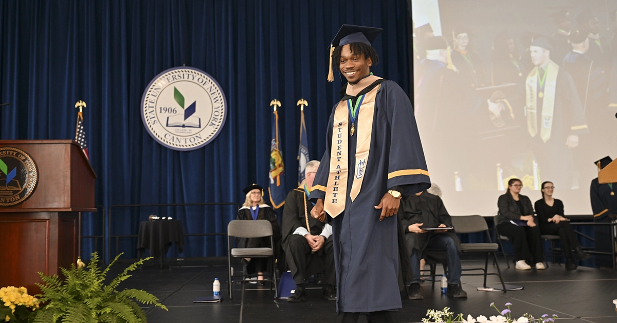 A graduates is all smiles as his name is announced from the Commencement stage.