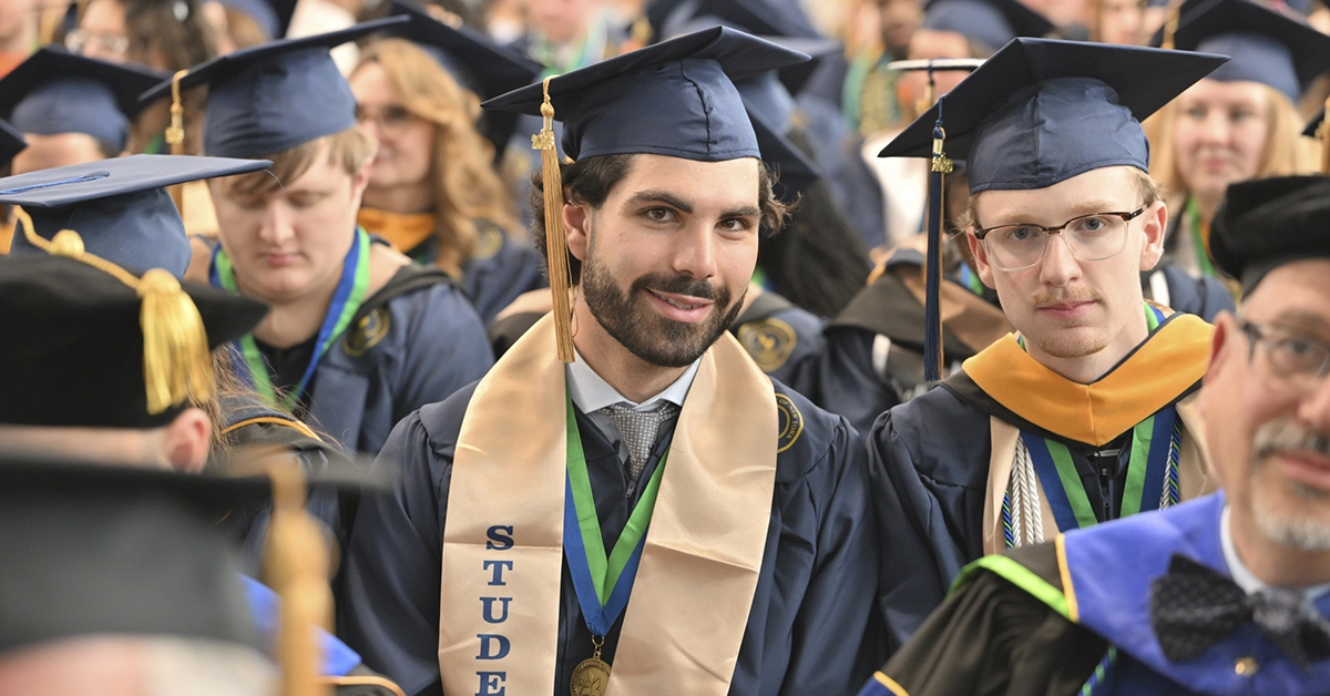 Two graduates pose in their regalia from the  Commencement 2026 audience.