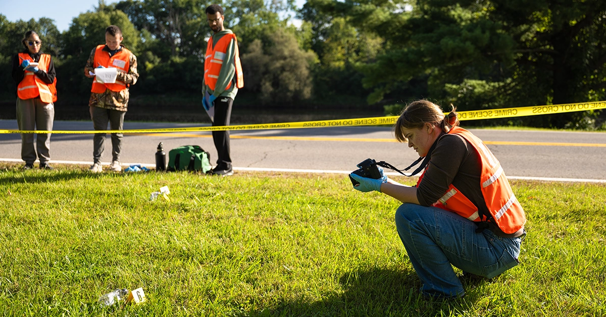 Crimina Justice students photograph a mock outdoor crime scene.