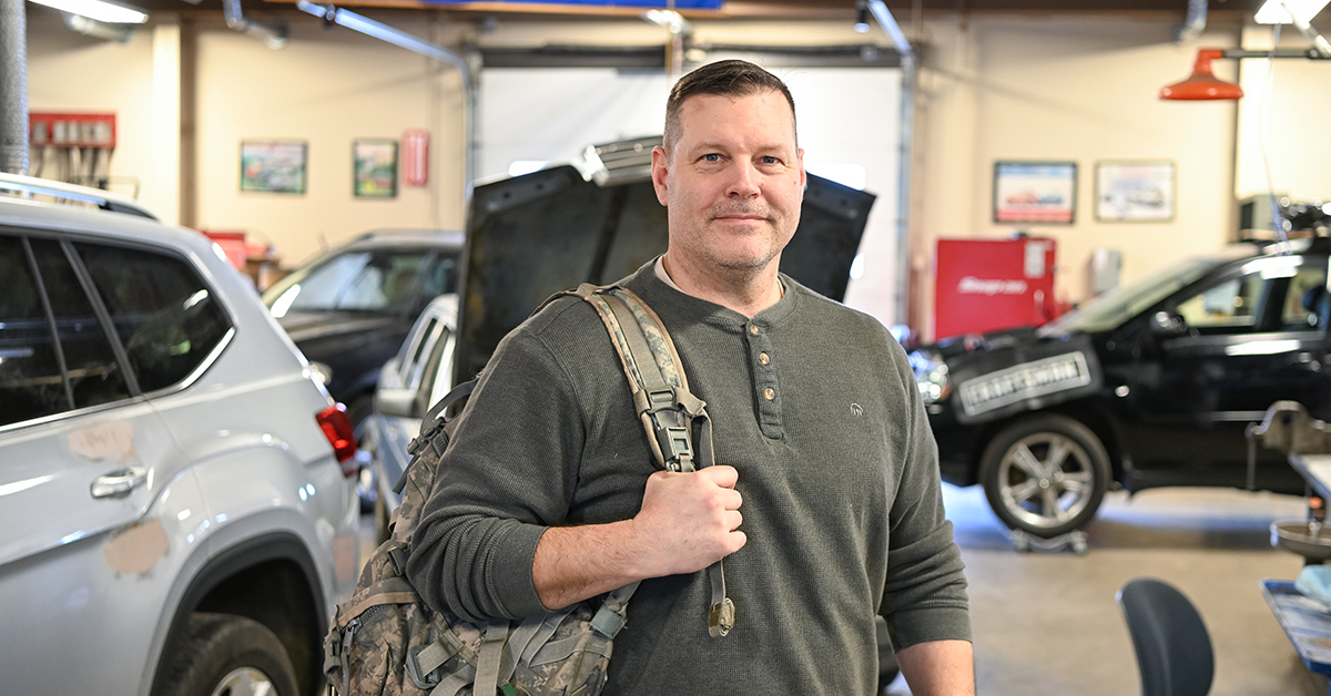 Eric Armstrong stands with a military backpack in the Automotive Lab.