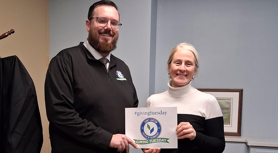 Chris Chambers and Melissa Evans hold a Giving Tuesday sign.