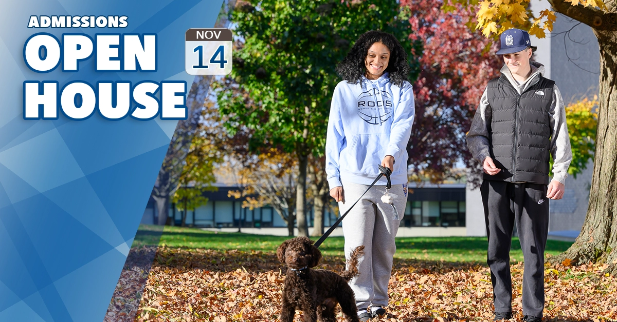 Admissions Open House - Nov. 14. Two students walk a brown goldendoodle through autumn leaves.