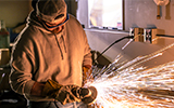 Samuel Servati grinds a part while sparks fly around in the Mechanical Engineering Tech lab.