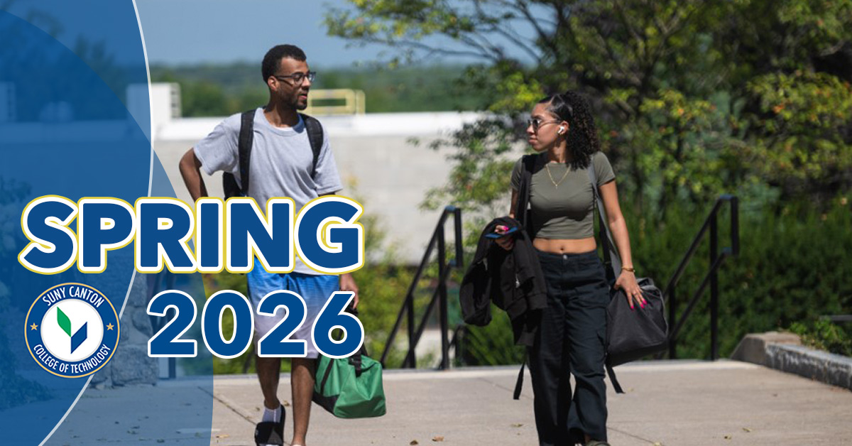 Spring 2026: Two students walk on the sidewalk next to Payson Hall.