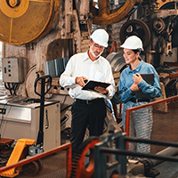 Two trades workers compare notes in an industrial facility.