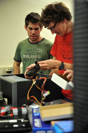 Students work on removing a video card from a desktop computer.