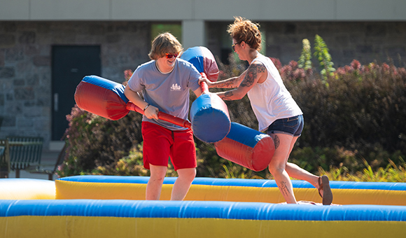 Two students battle with padded pupil sticks at Fall Fest 2024.
