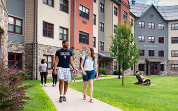 Two students walk down the sidewalk outside Kennedy Hall.