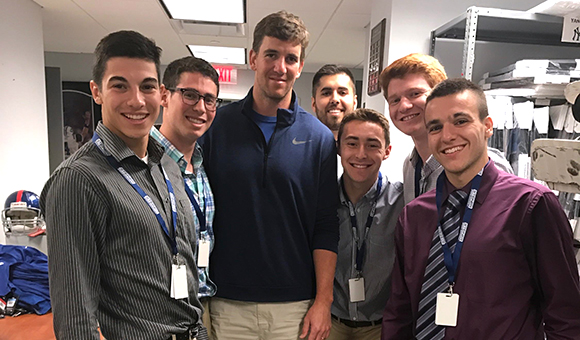 Francesco Palumbo, '18 poses with New York Giants quarterback Eli Manning (center) and other interns during an internship at Steiner Sports in New York City.