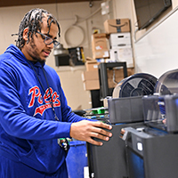 A students uses a 3D printer in the Mechatronics lab.