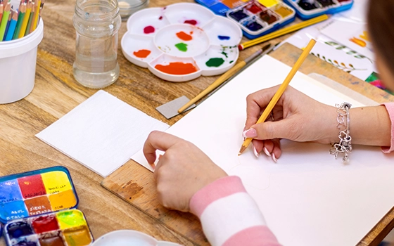 A camper draws and paints at a desk.