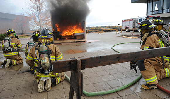 Firefighters line up to extinguish a mock burn.