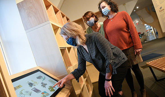 Laura Ettinger, Alainya Kavaloski, and Vegh Williams view the new History of North Country Childhood display.