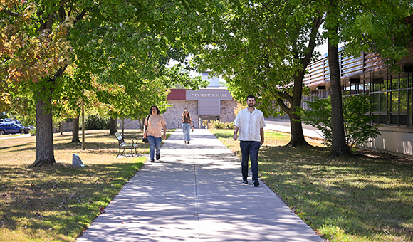 Three students walk down the sidewalk outside Nevaldine North during the first week of classes.