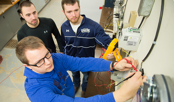 SUNY Canton Air Conditioning Engineering Technology students Zackary T. Flanagan, Brendan J. Jerkowski and Garrett J. Fields measure a feedback signal on a newly constructed training board for air handler devices located in the college’s Harry King Air Conditioning laboratory.
