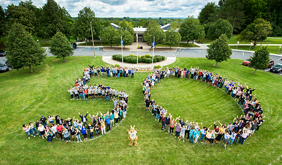 Students, faculty, and staff form a 50 on the lawn in front of French Hall.
