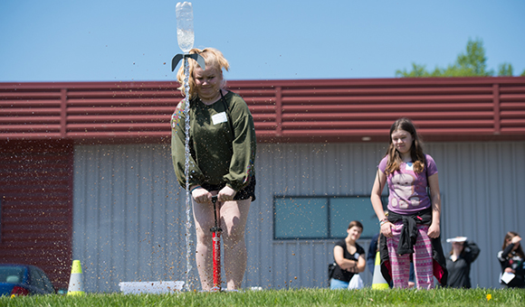 A student launches a bottle rocket outside of Nevaldine Hall