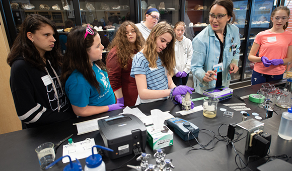 Students gather around Adrienne Rygel as she teaches about water filtration.