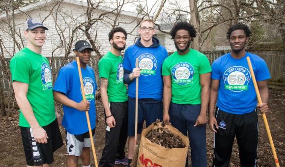 The Men's Basketball team poses in front of a bag of leaves.