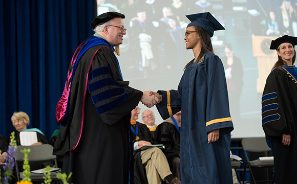 President Szafran congratulates a student on stage.