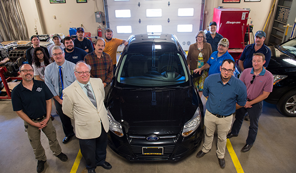 President Szafran, students, and staff surround the new Ford Focus.