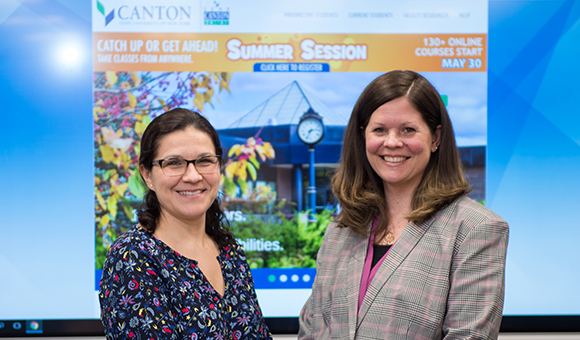 Marela Fiacco and Michelle Currier stand in front of a projected SUNY Canton OnLine Website.