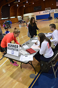 Students work the Runner Registration table.
