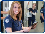 A nursing student holds a clipboard in the simulation lab.