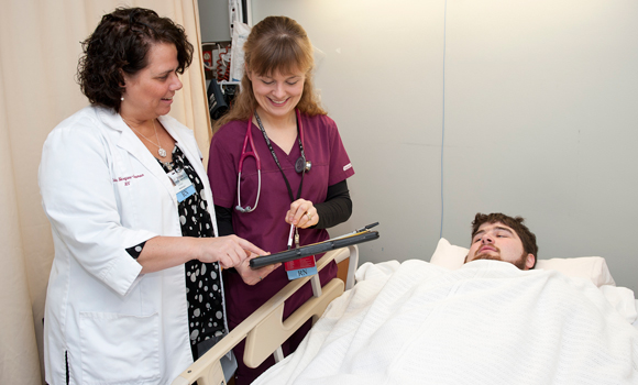 Two nurses check in on a patient.