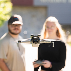 Two students navigate a hovering drone.