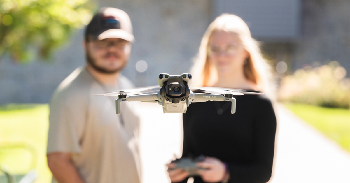 Two students navigate a hovering drone.